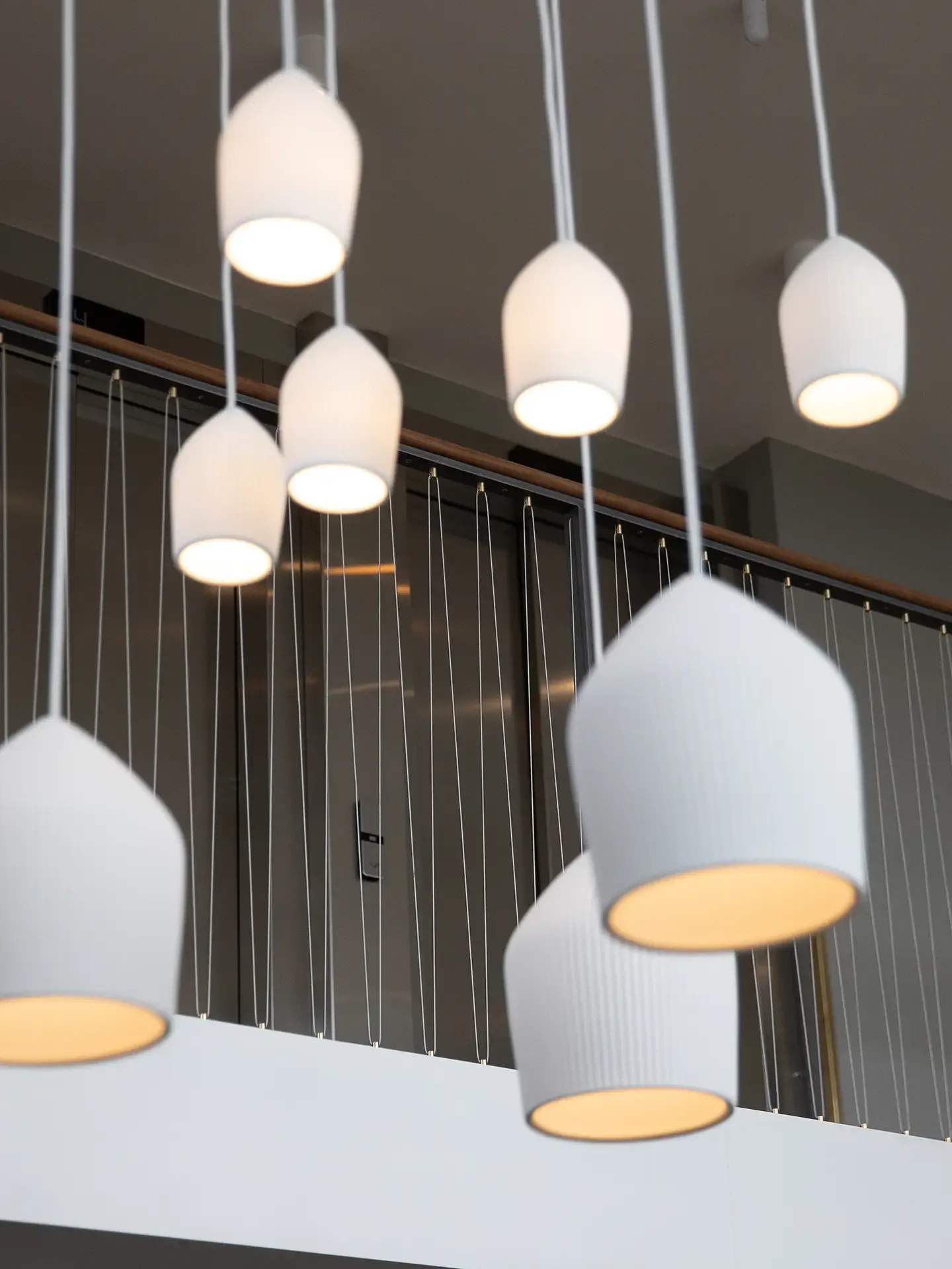 Cluster of modern ceiling pendant lights in hotel interior.
