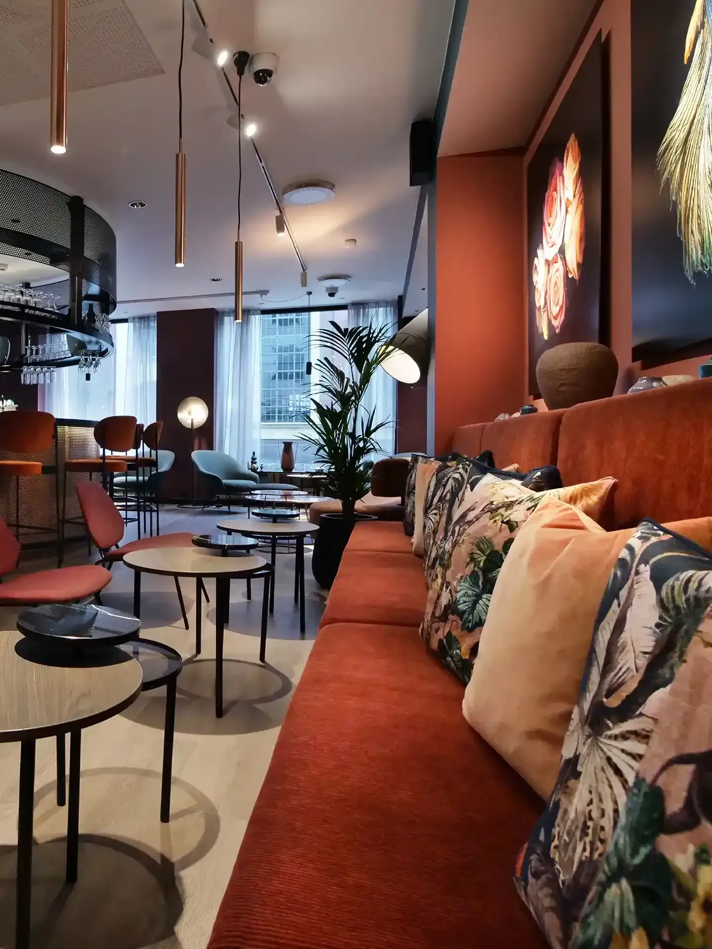Colourful bench seating with botanical cushions and warm orange tones – a playful yet elegant hotel lounge bar design.