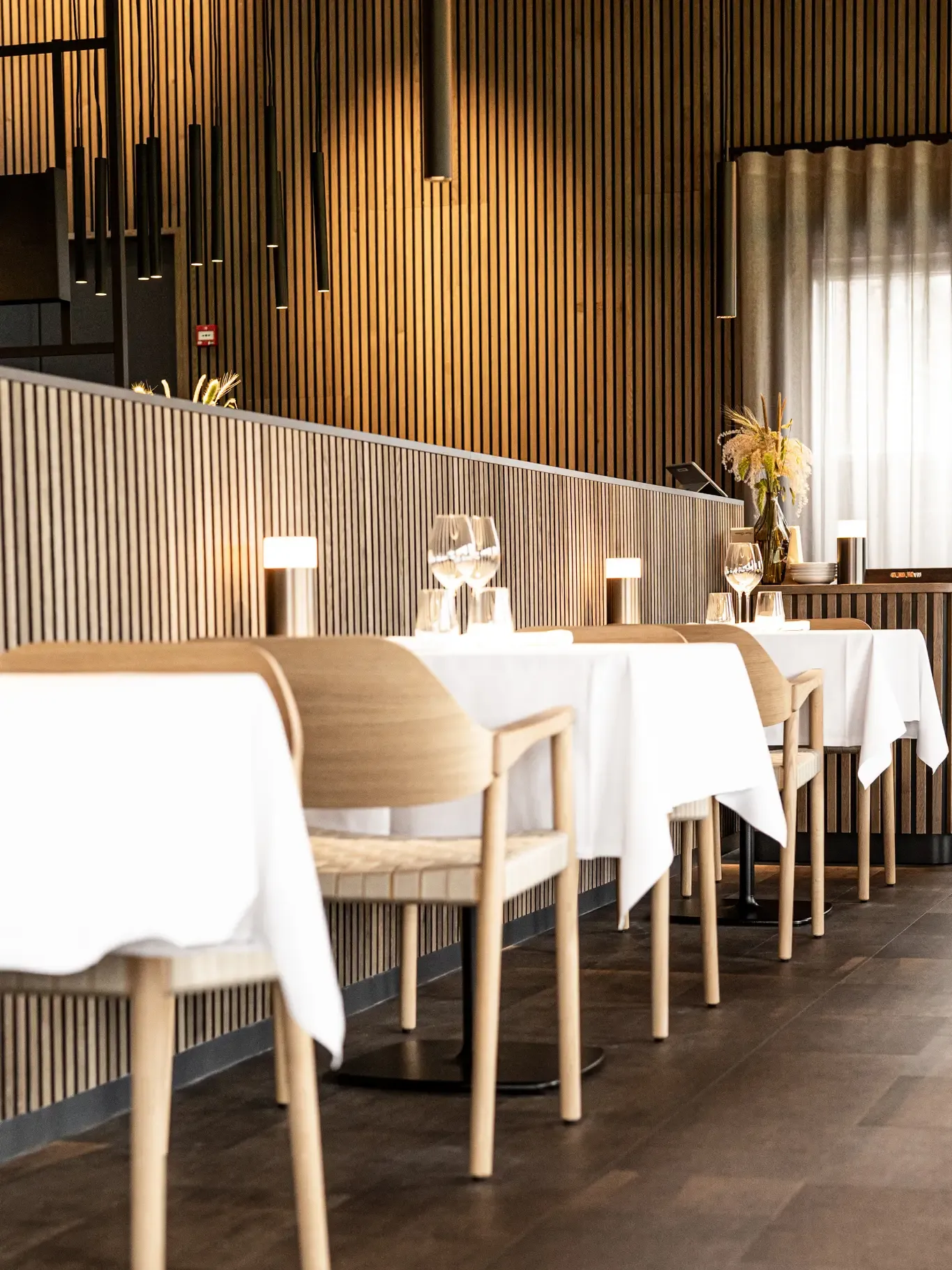 High-quality restaurant design with oiled oak wood, acoustic panels with elegant tablecloths and lighting.