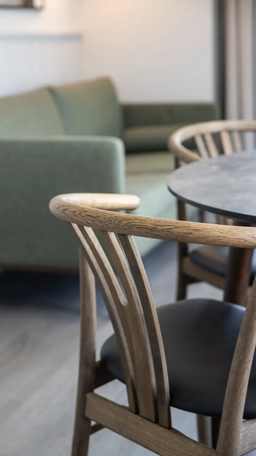 Hotel room dining table paired with green upholstered sofa. Homely feel and flexible interior.