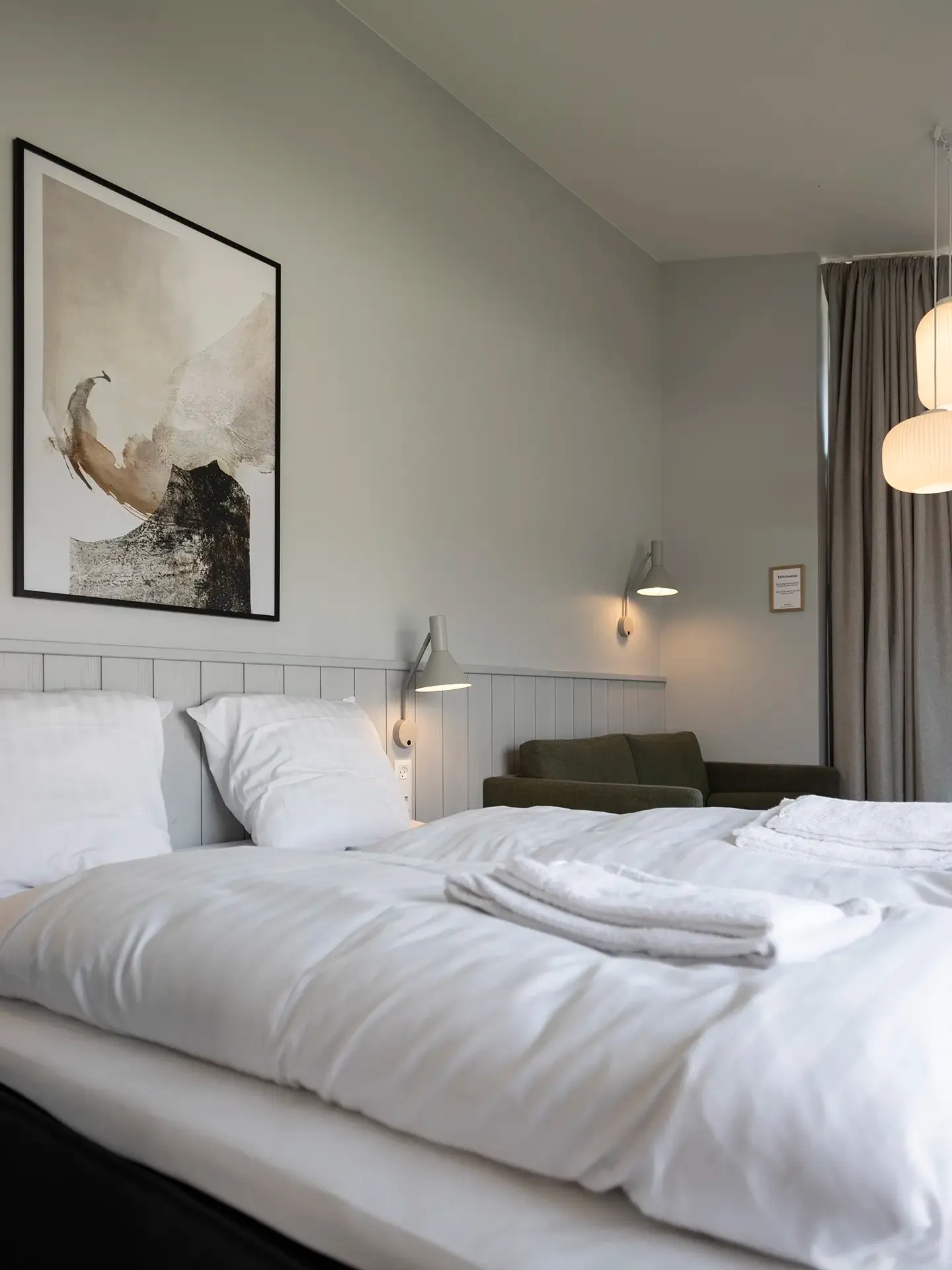 Double bed in Scandinavian-style hotel room interior. White bedding and calm colour palette.