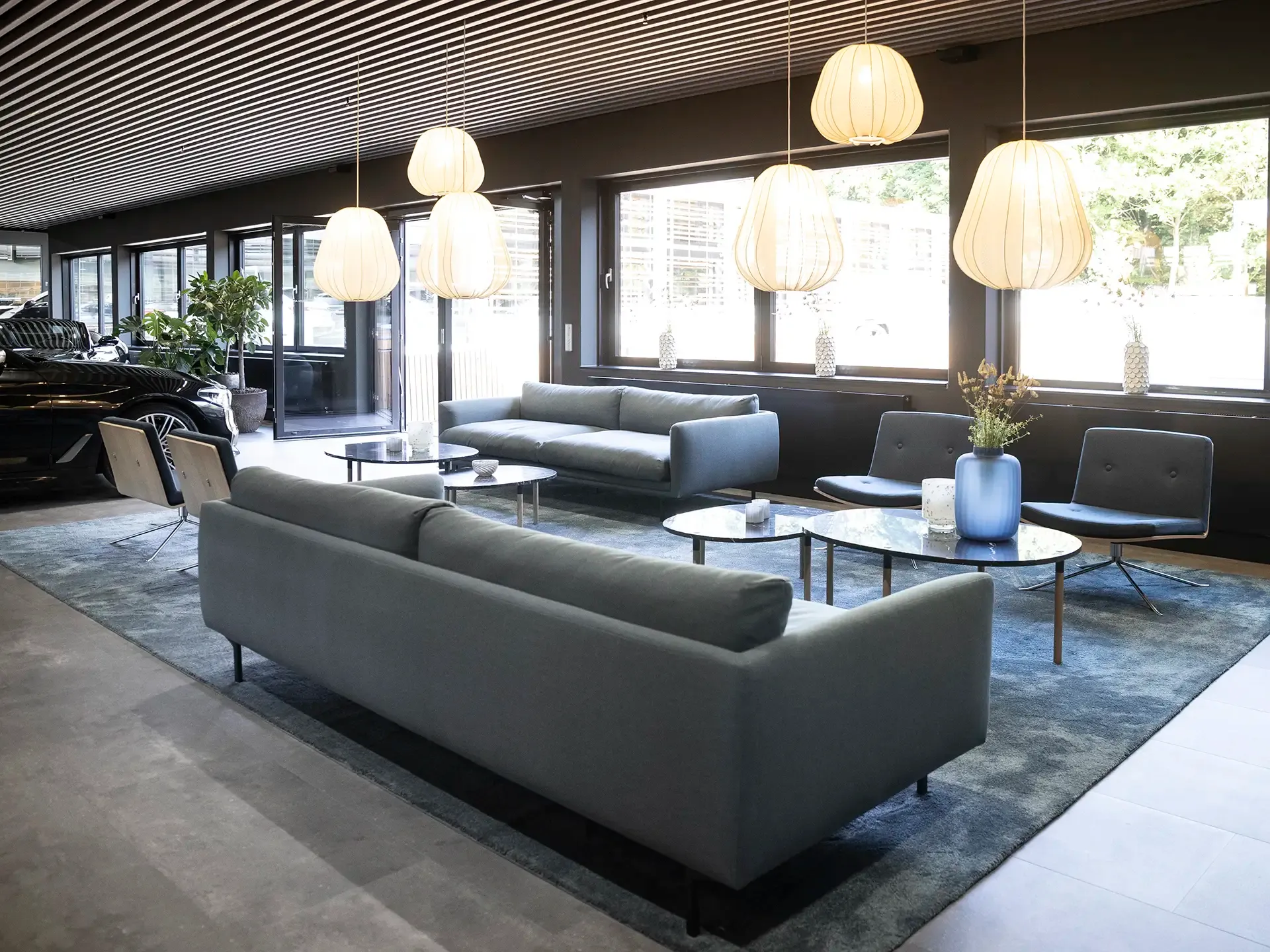 Modern lounge area with blue Bolia sofas and pendant lights for Nordic-inspired showroom design.