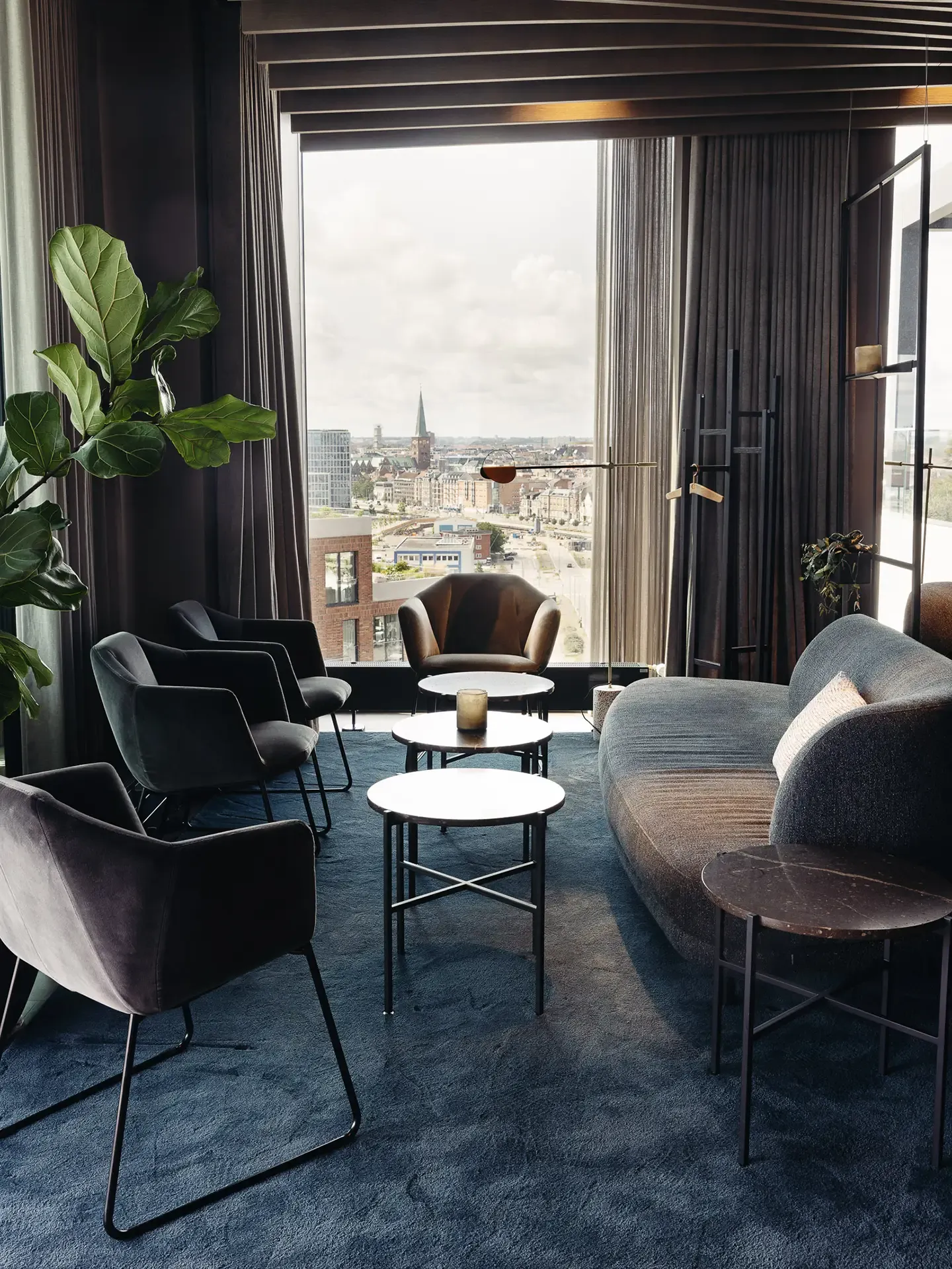 Restaurant lounge with sofa and armchairs in dark tones, designed for intimate guest seating and a refined dining atmosphere.