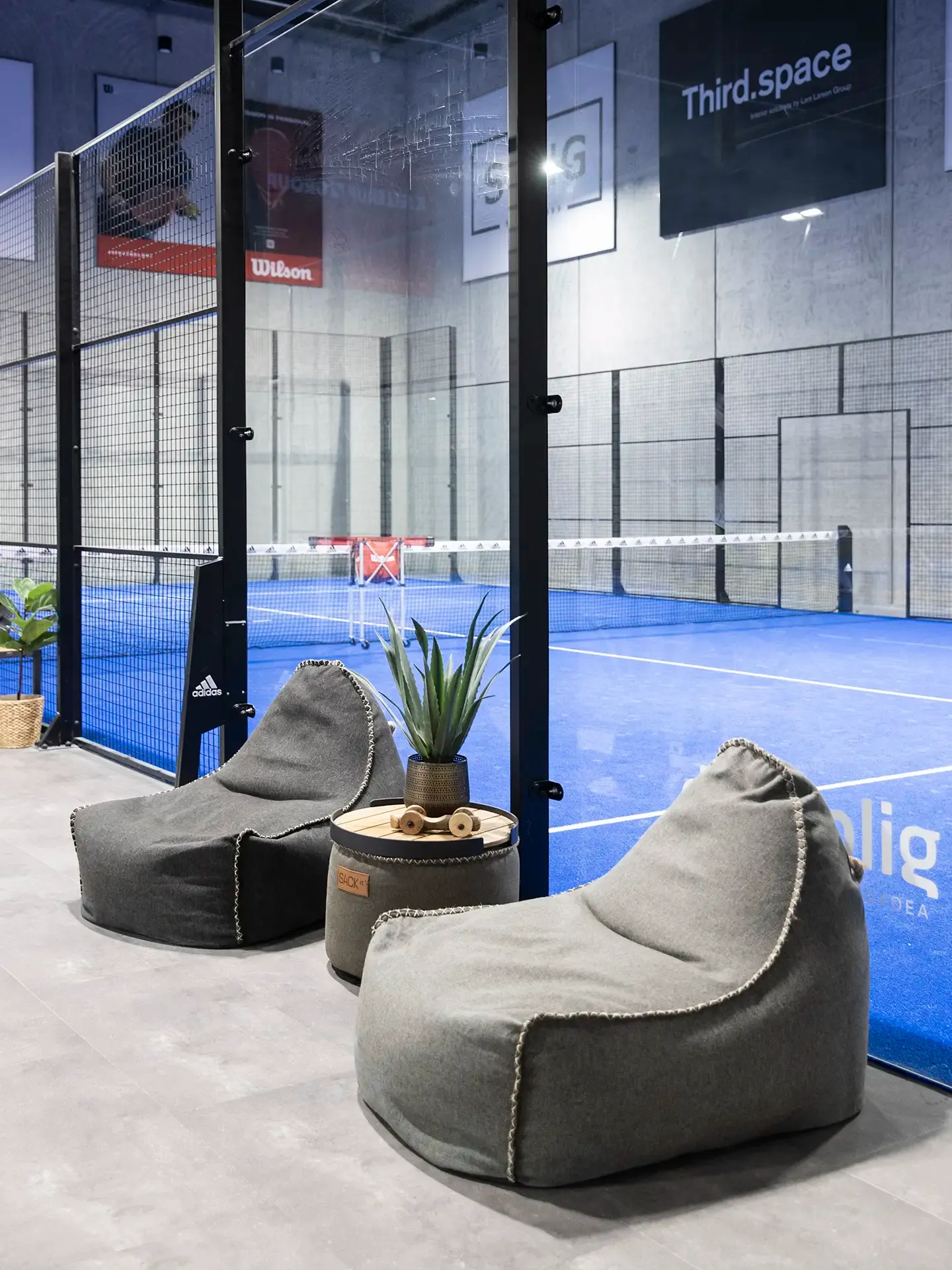 Casual chill-out area with soft beanbag chairs near padel courts, perfect for younger members and flexible club lounge use.