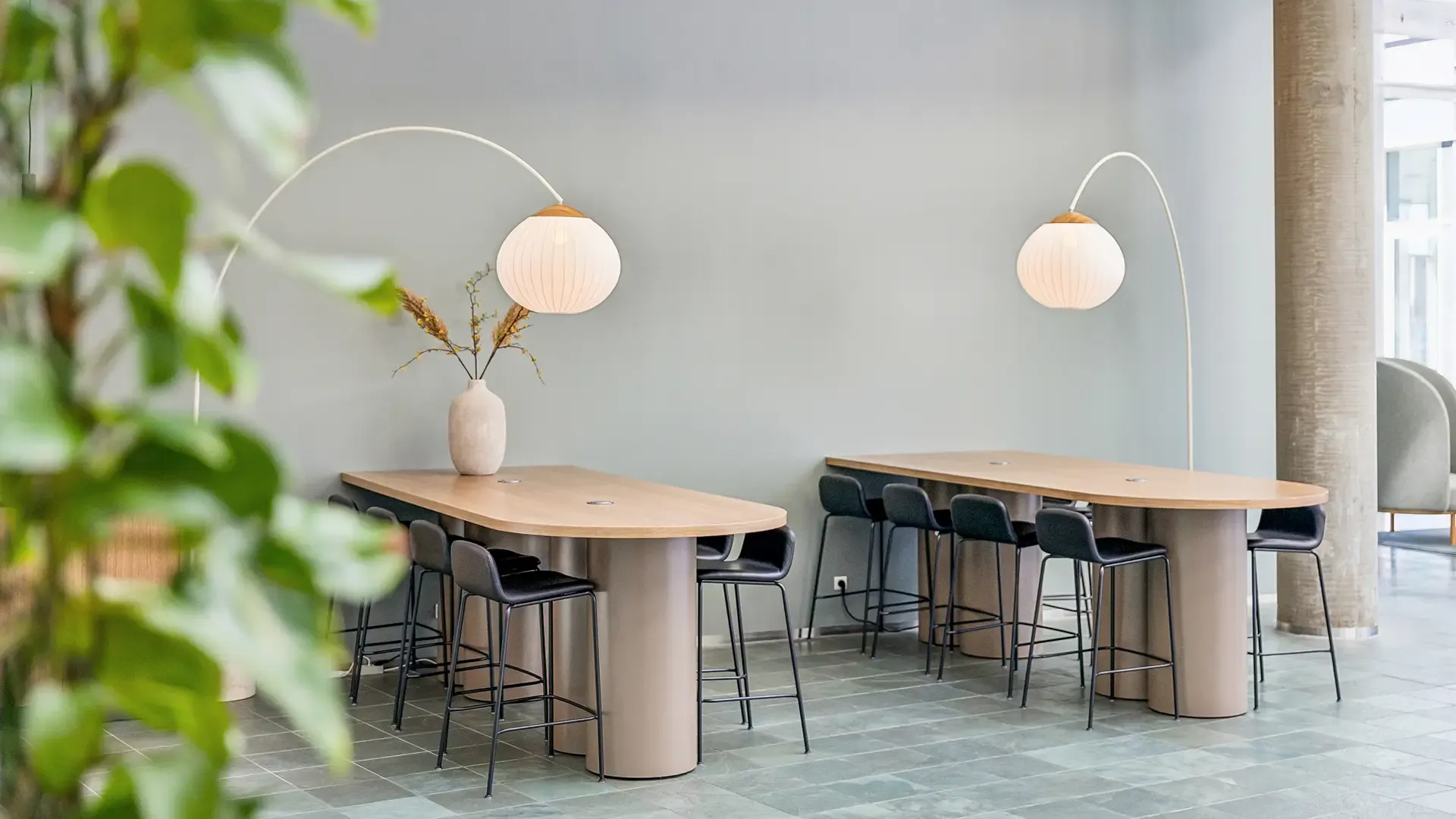 Collaborative office workspace with high tables and wood lamps, designed for teamwork and flexible working environments.