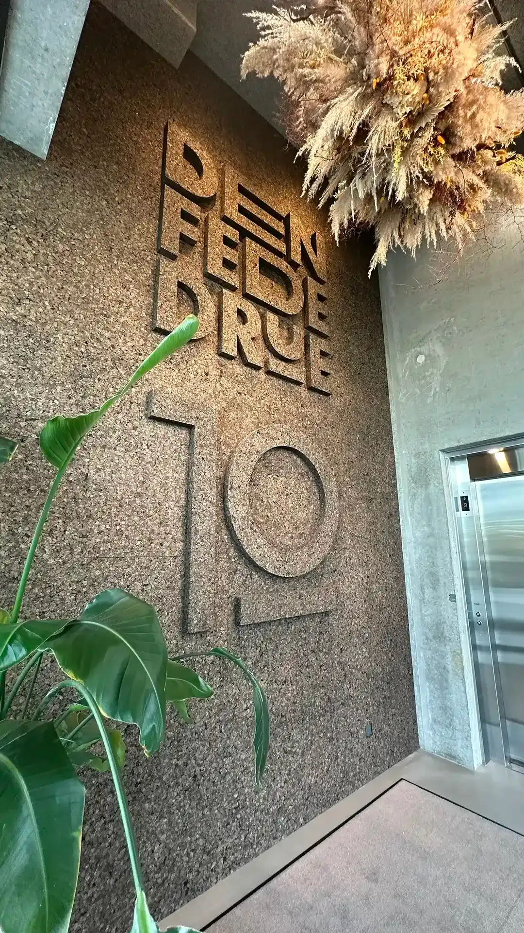 Restaurant entrance with cast concrete wall and cork planting, creating a natural and tactile first impression for guests.