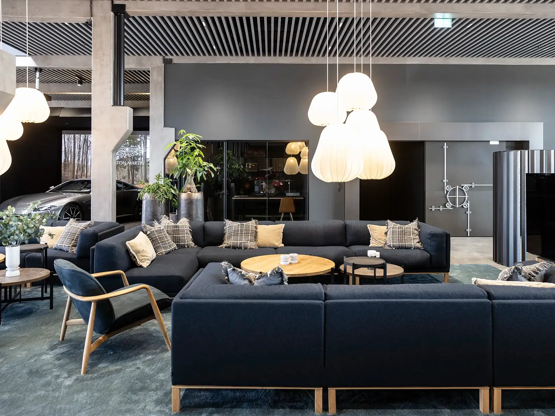 Luxurious showroom lounge with dark blue sofas and soft lighting, designed for premium client comfort.