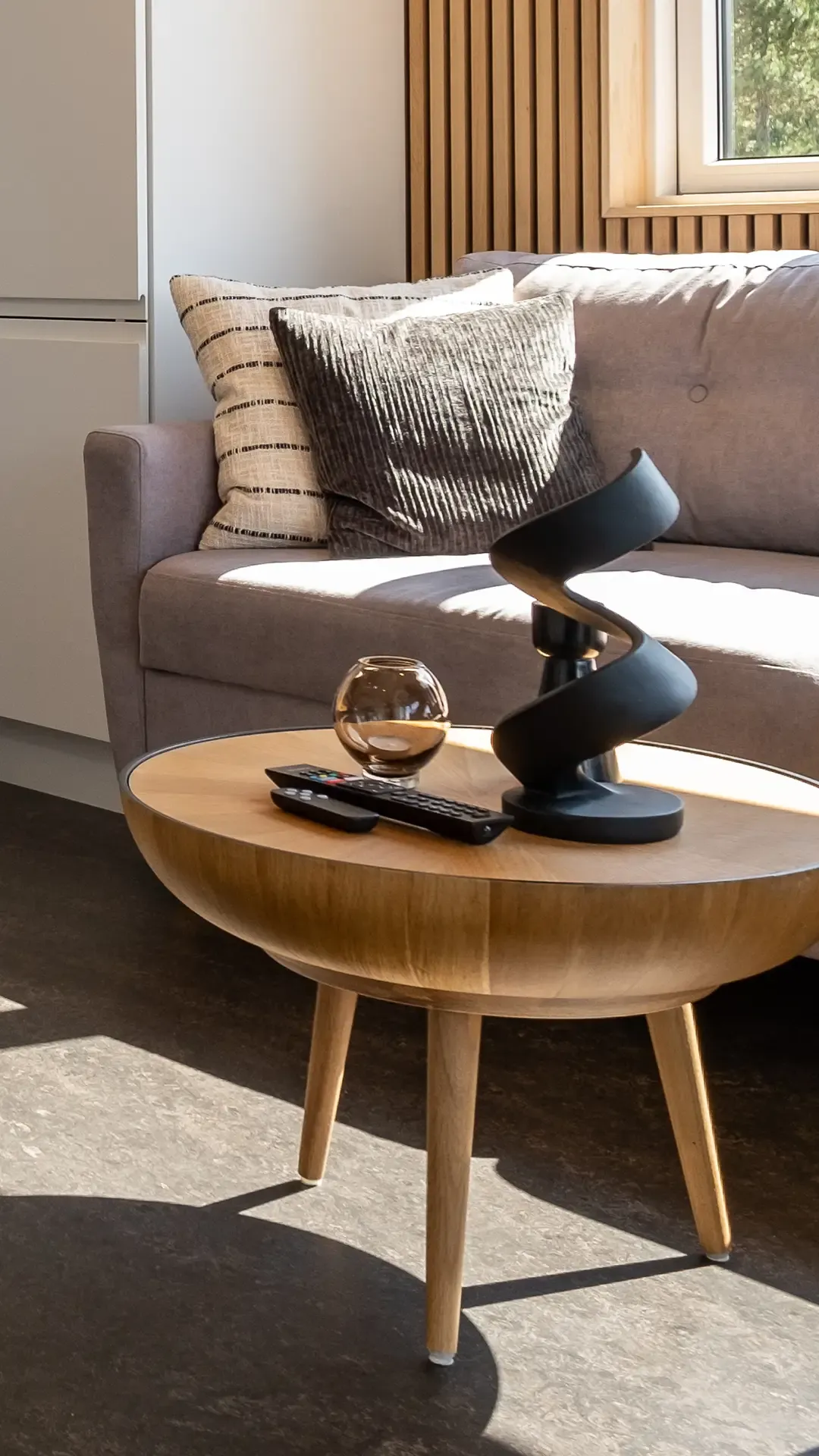 Detail of round oak coffee table with Nordic decorative items in stylish camping cabin living room – Scandinavian interior accents for holiday retreats.