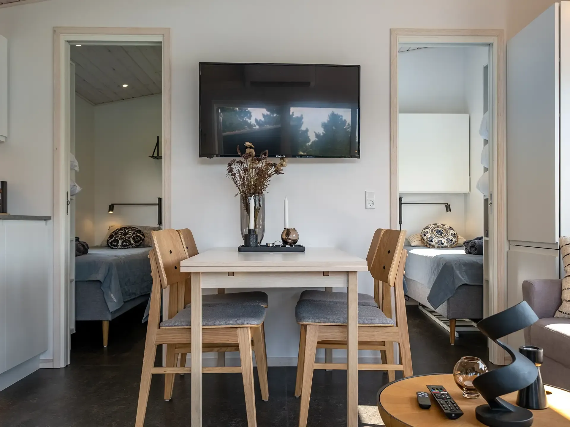 Cozy Nordic cabin interior with oak dining furniture, TV and lounge area – Scandinavian layout optimized for compact holiday home spaces.