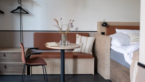 Cozy short-stay apartment with integrated bedroom and dining corner, designed to optimize space and guest comfort in hospitality projects.